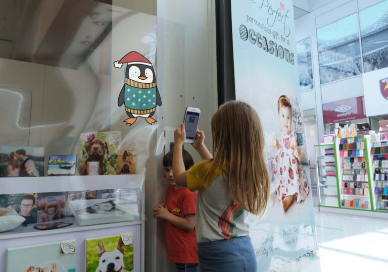A child scans the QR code of a festive penguin character