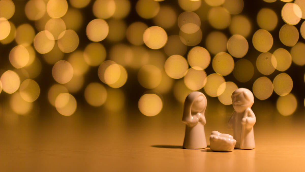 Small figures of Mary, Joseph and baby Jesus in front of golden lights