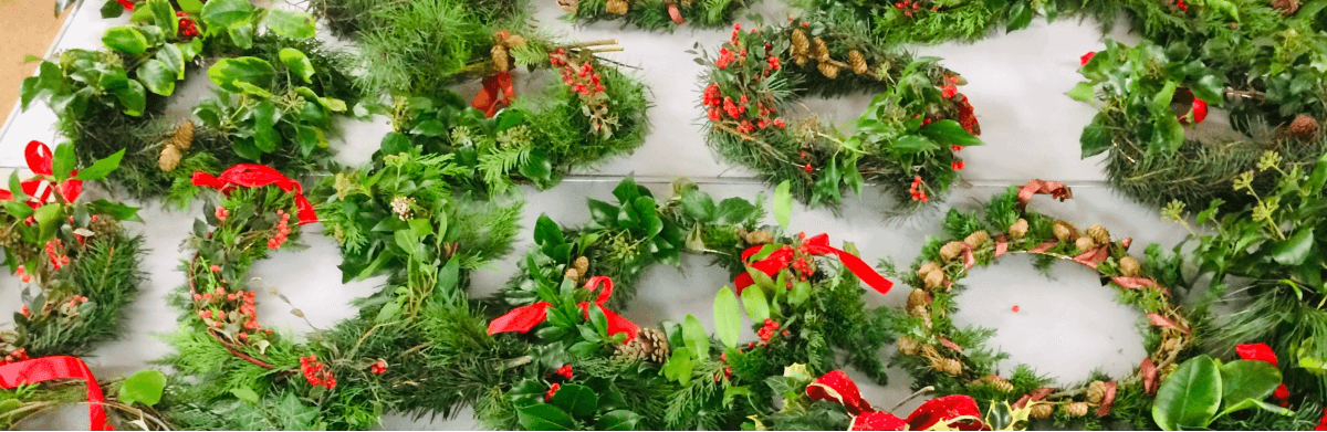 Christmas Wreaths laid on a table with red festive ribbons