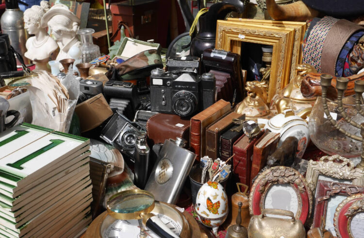 A stall at a flea market filled with items to sell, tiles, picture frames, bits and bobs.