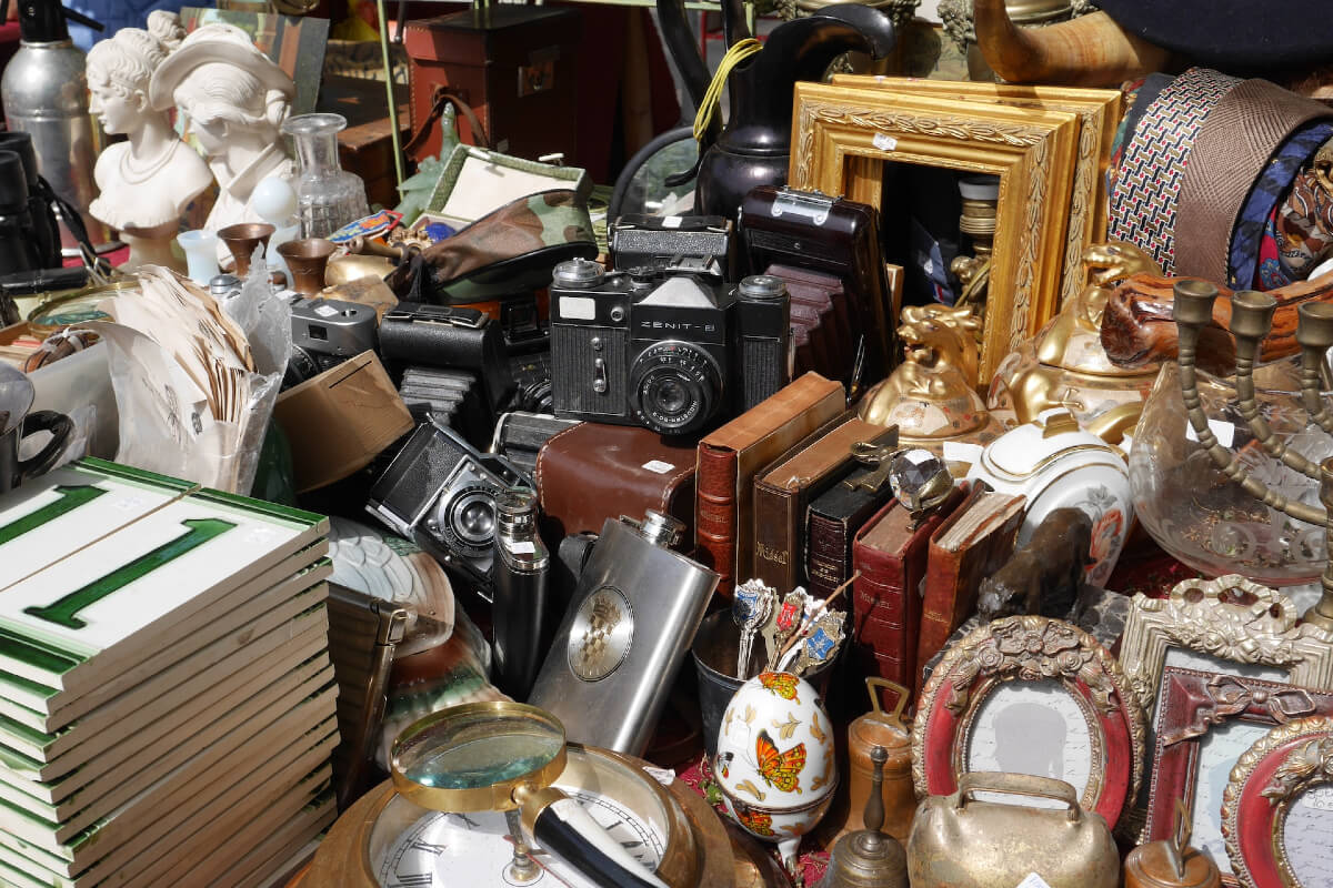A stall at a flea market filled with items to sell, tiles, picture frames, bits and bobs.