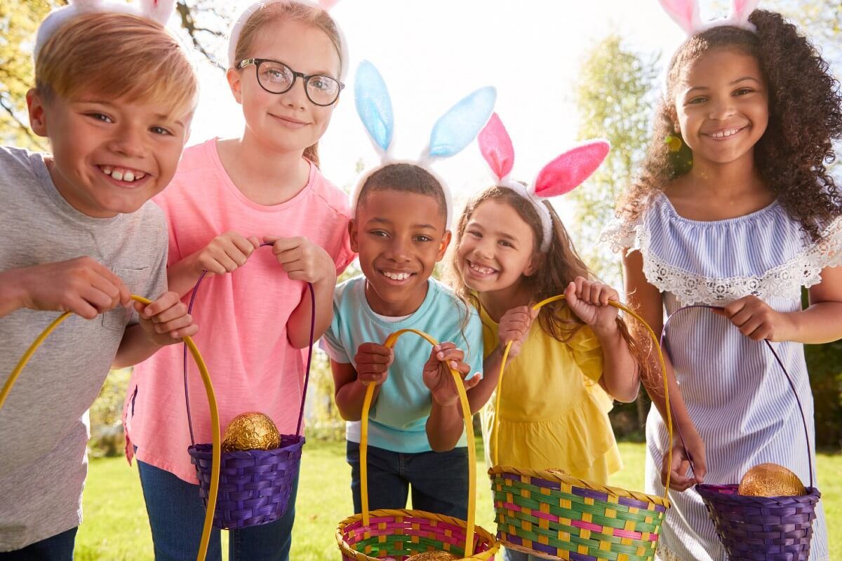 Five children with bunny ears show off their egg baskets
