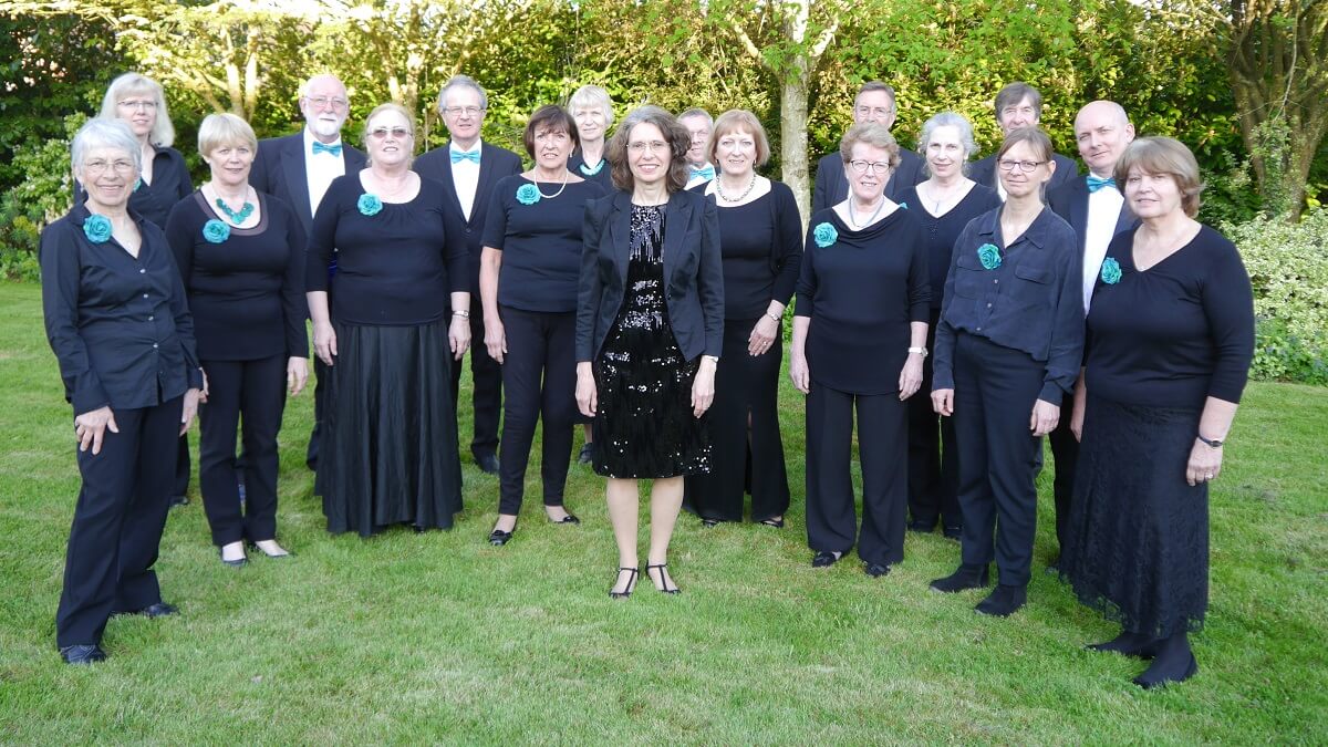 The Hills Singers standing on grass with trees in the background