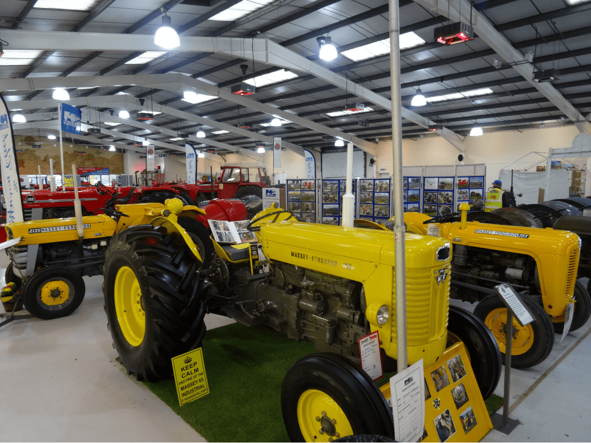 A warehouse full of tractors with a bright yellow tractor in the foreground