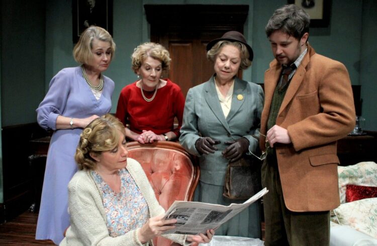 Four women including Miss Marple and one man study a newspaper
