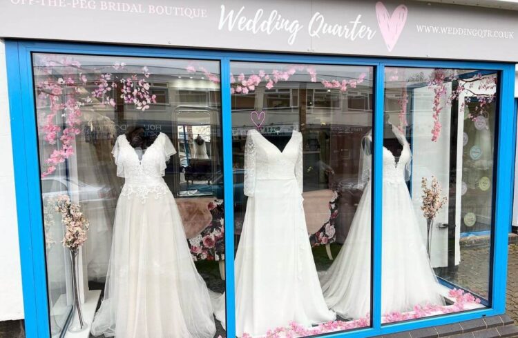 A wedding dress shop frontage displaying three white wedding dresses