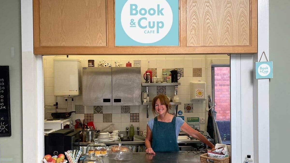 The kitchen and counter at Book and Cup Cafe, with sweet items and fruit on display