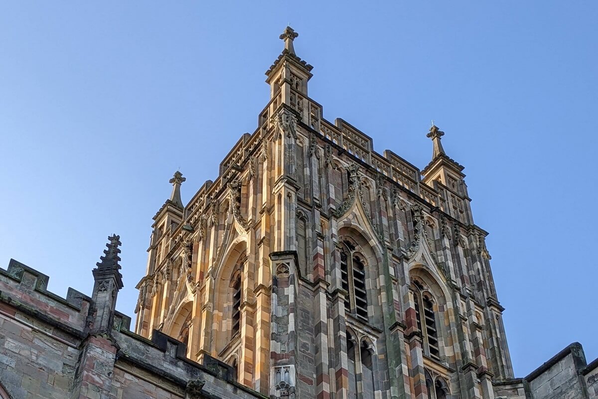 A view of Great Malvern Priory tower with blue sky in the background