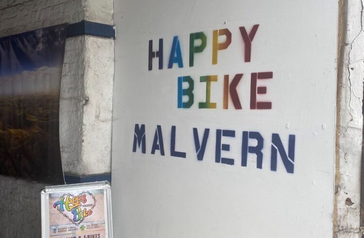 Rainbow writing on a white wall that spells happy bike