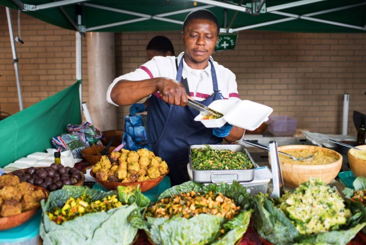 A person serving vegan food at a market