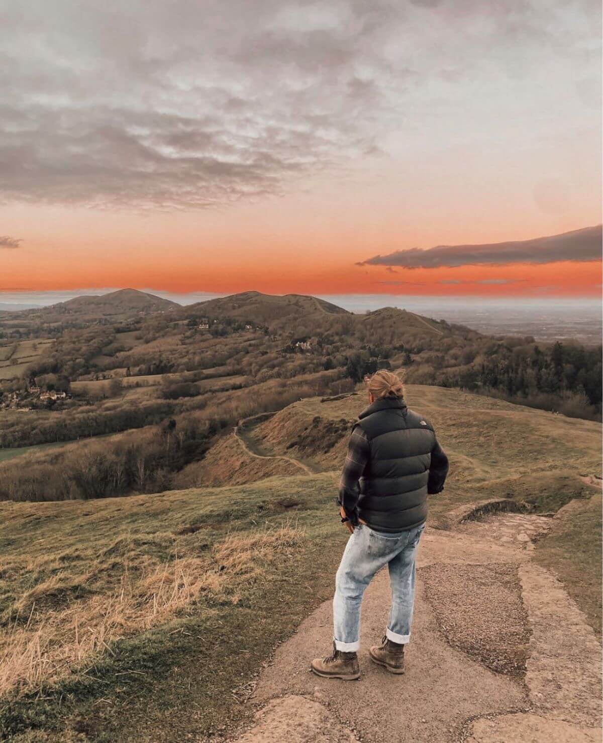 A person watching the orange sunset over the Malvern Hills