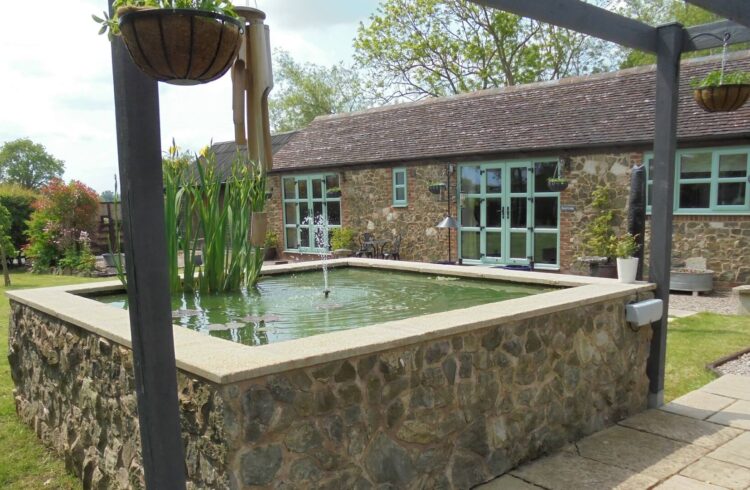 Outside area at Beech Lodge with pond, hanging baskets, grass