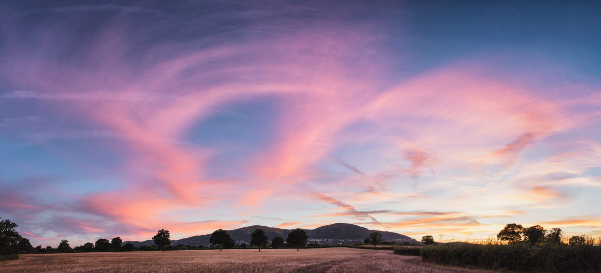 The Line of the Malvern Hills at sunset with pink clouds and blue sky behind