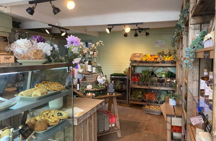 Small local produce deli with flowers, wooden shelving and sage green walls