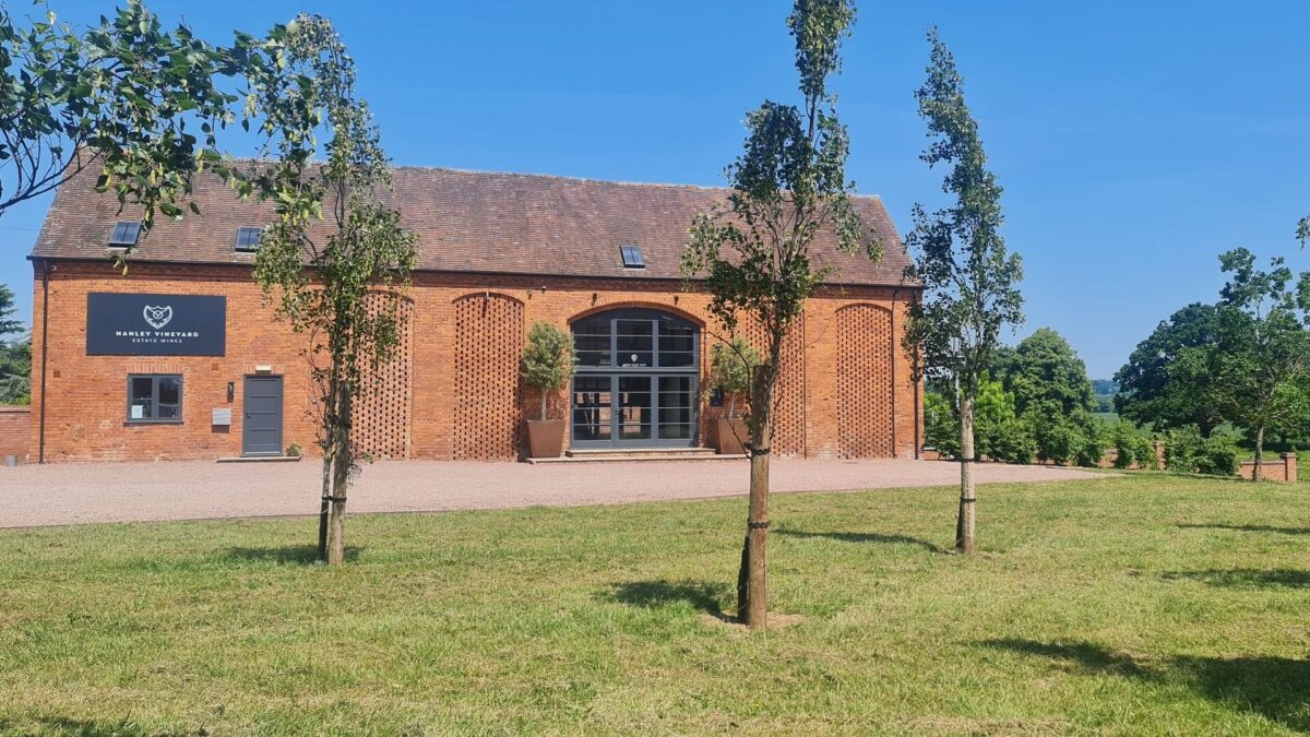Exterior view of converted barn at Hanley Vineyard with grass and trees to front