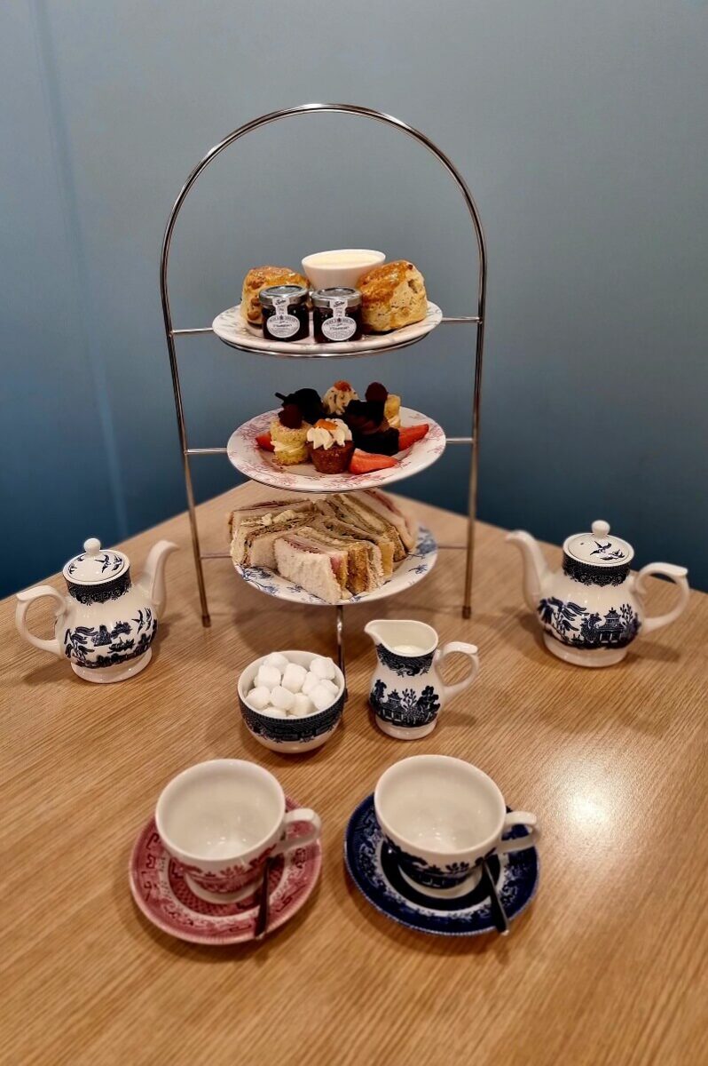 Afternoon tea served on a stand with vintage teapot and cups