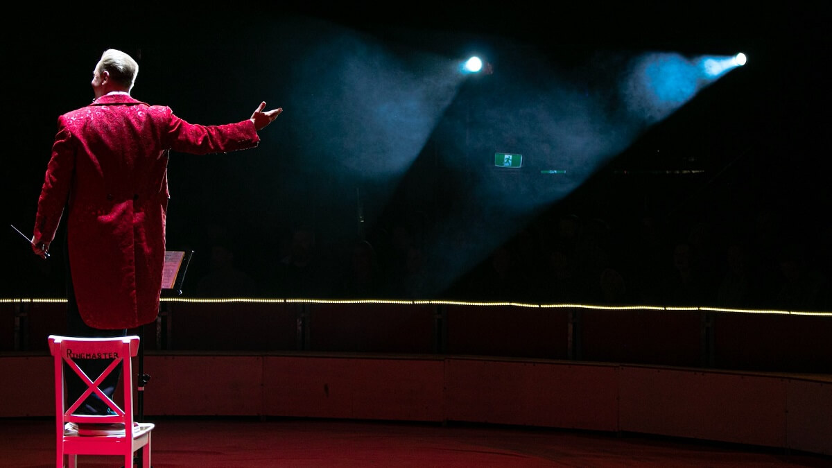 Circus ringmaster dressed in red facing the audience