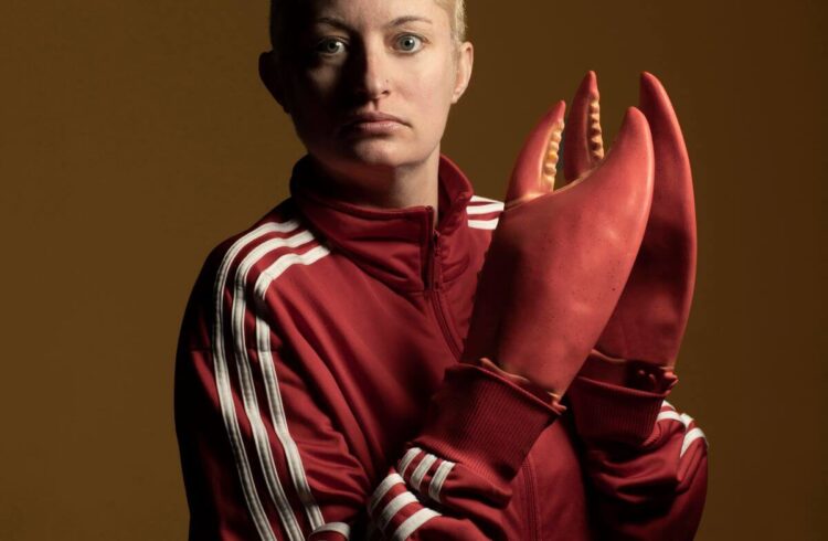 A person dressed in red with fake lobster claws on their hands