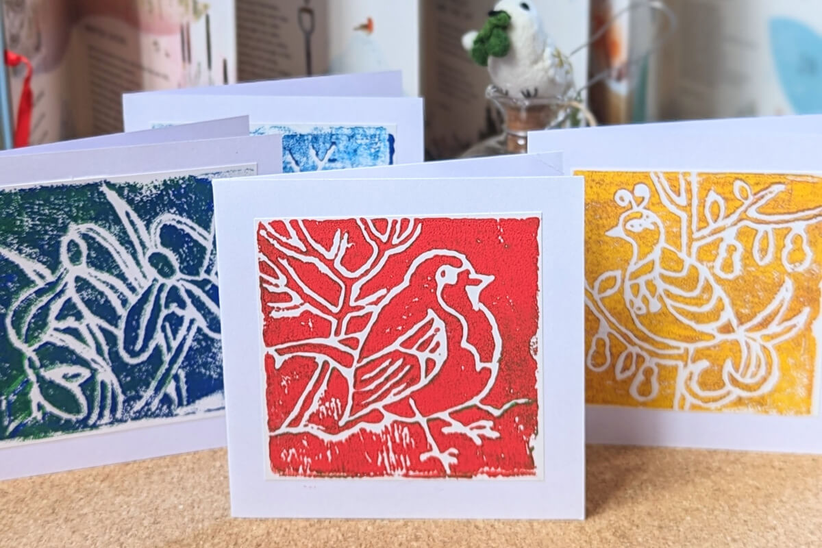 Images of Lino printed Christmas cards. A robin in red ink, snowdrops in blue ink