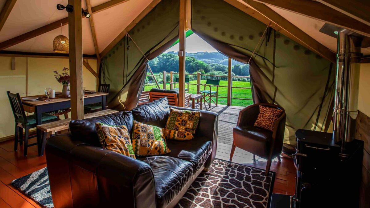 Interior of Hakuna Matata Safari Lodge with sofa, chair, dining area and views of countryside beyond