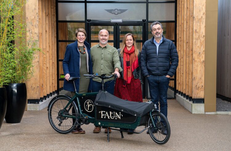 Four people stand outside a building with a cargo bike in front of them