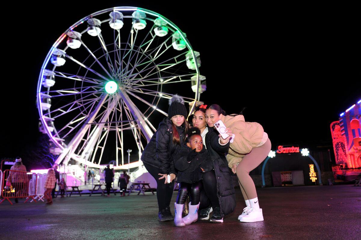 A group of people taking a selfie in front of an illuminated Ferris wheel