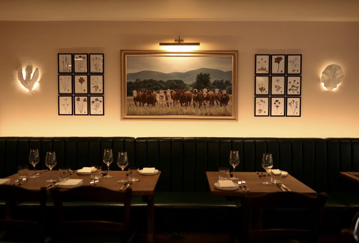 Restaurant interior with green built in seating and cow artwork