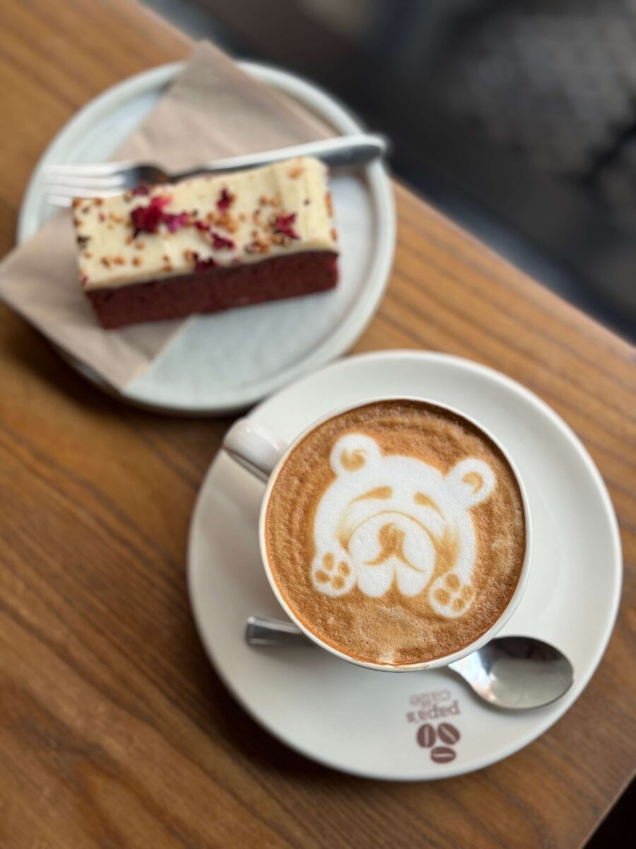 A plate of cake and a latte with a bear created in the foam