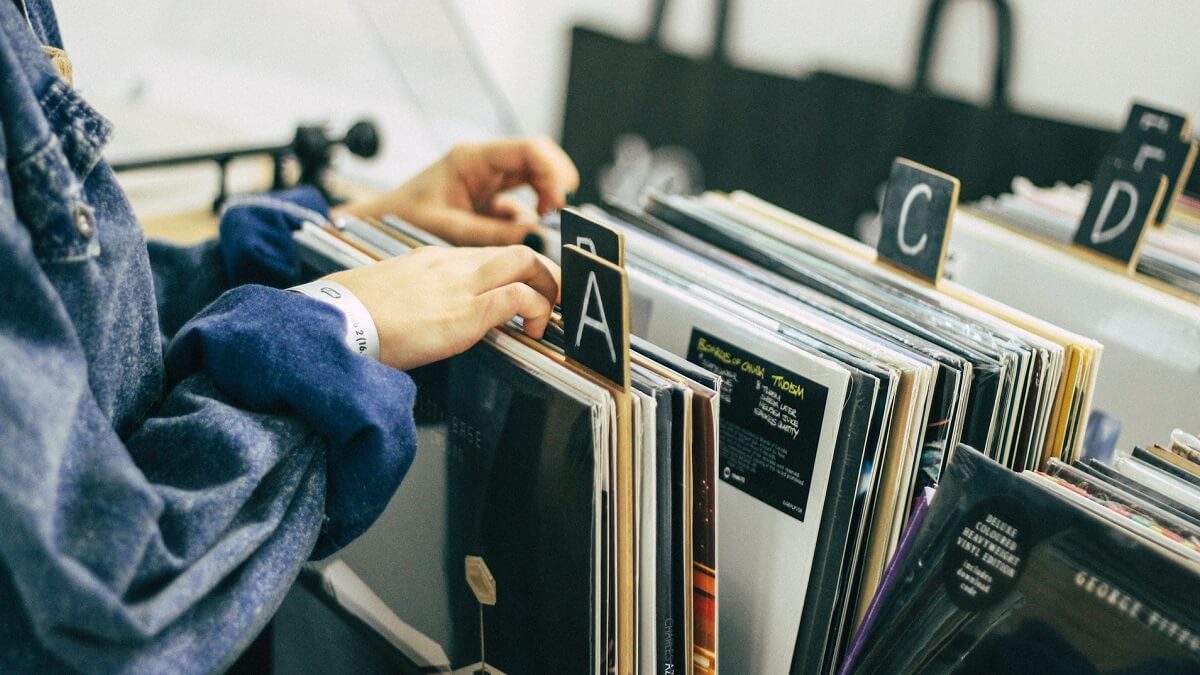 A person looking through vinyl records arranged alphabetically