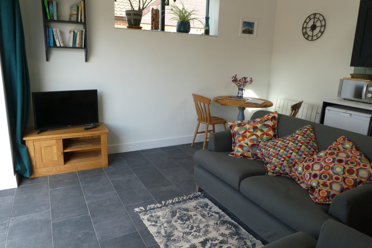 A living room with a grey sofa and floor tiles