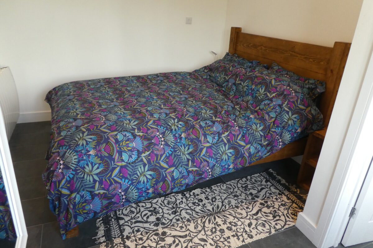 A bedroom with a colourful bed spread