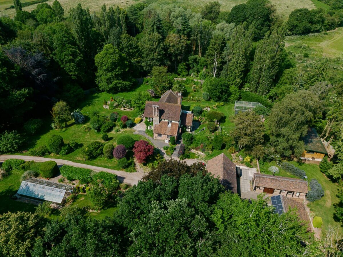 An aerial view of an English country house with green surrounding gardens and outbuildings