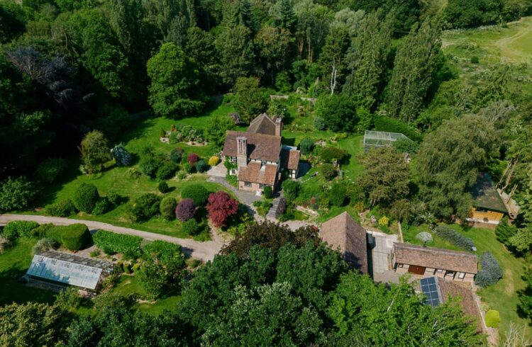 An aerial view of an English country house with green surrounding gardens and outbuildings