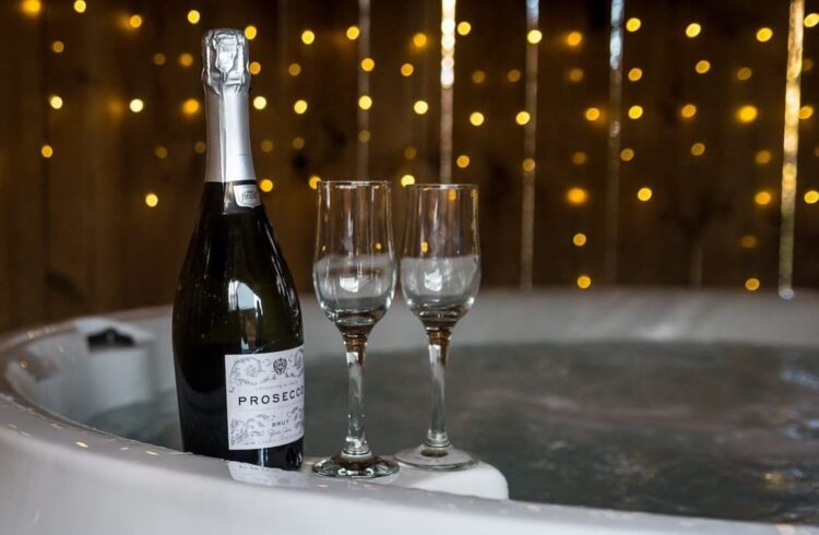 A bottle of Prosecco and two glasses by a hot tub