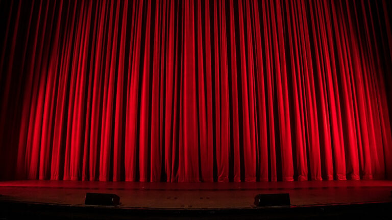 A red curtain across a theatre stage