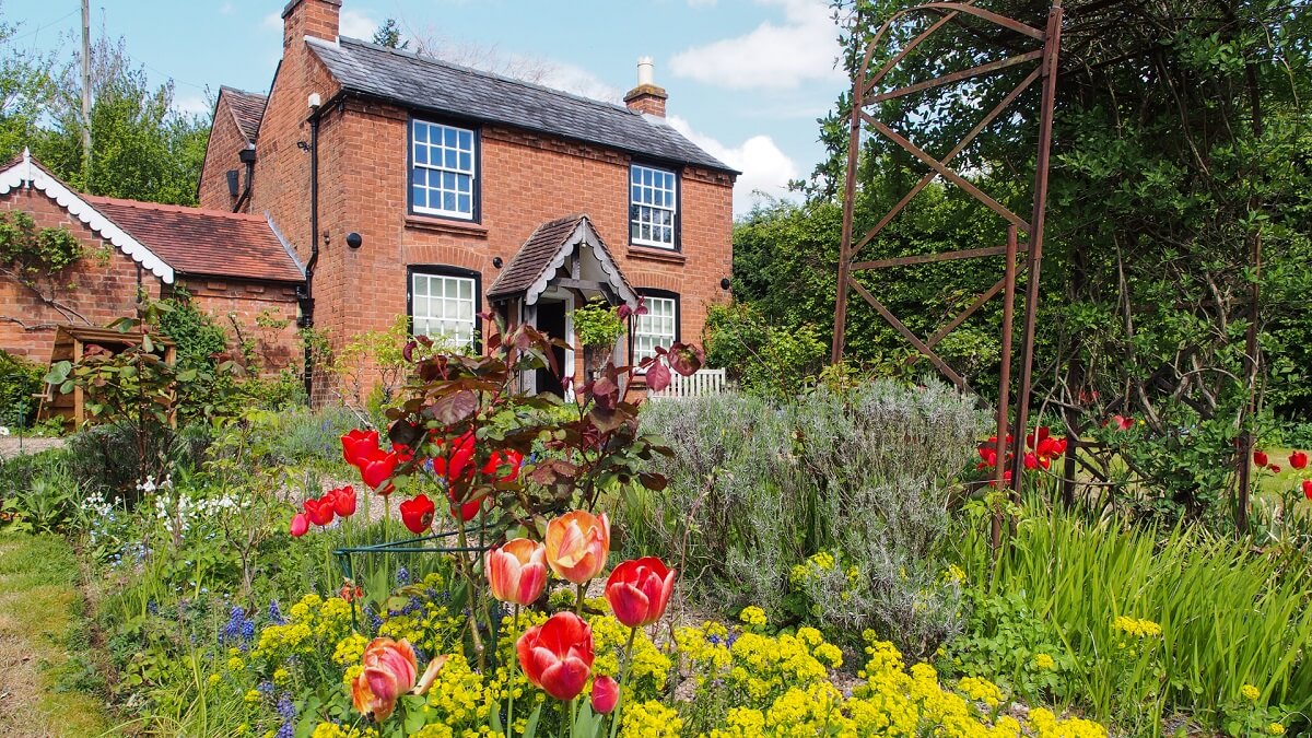 A view of the front of Elgar's birthplace cottage on a sunny day, with flowers in the front garden