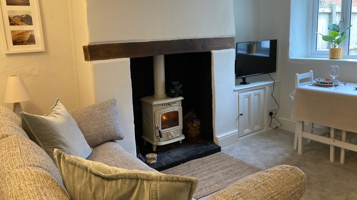 Cosy sitting room area with sofa, woodburning stove and dining table