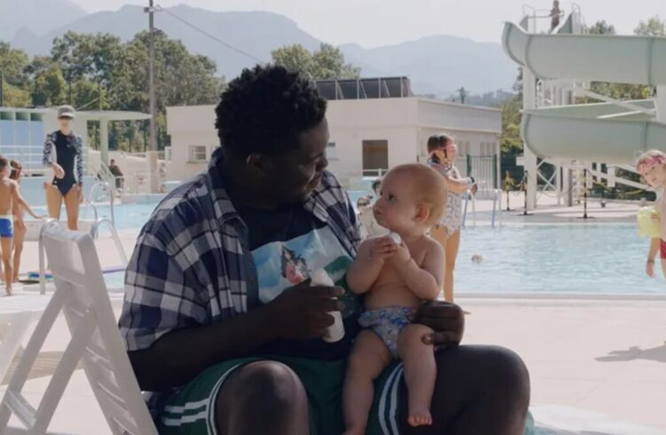 A still from the film showing an adult and baby at an outdoor water park