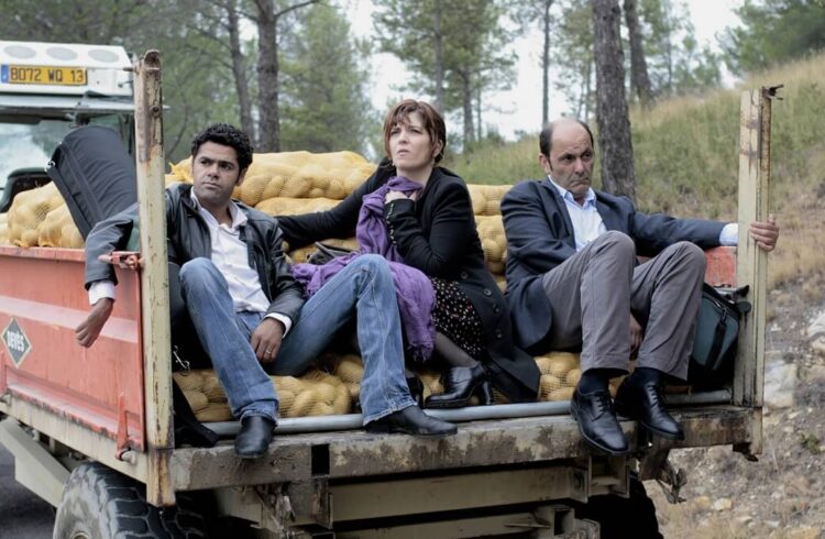 A still from the film showing three smartly people on a trailer being pulled by a tractor