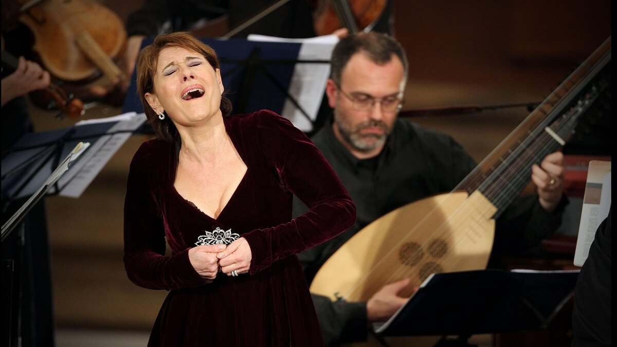 A female opera singers dressed in black, next to a male musician