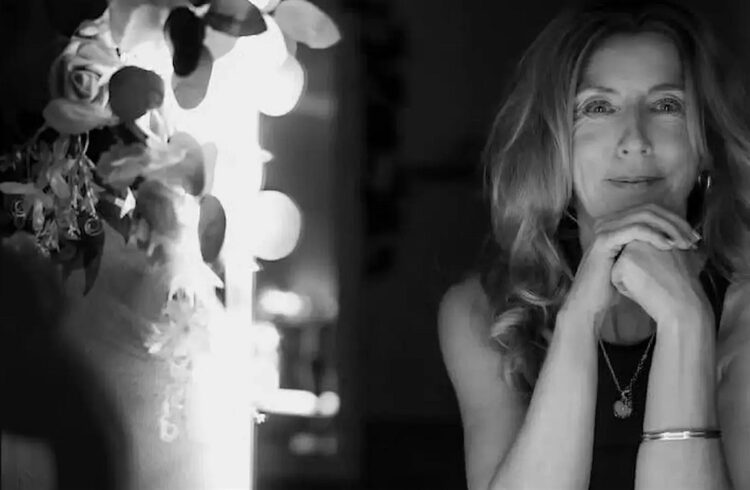 A B&W image of some lights (on the left) and a woman looking directly at camera (on the right)