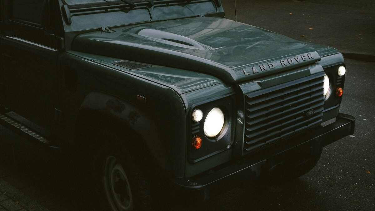 The front of a Land Rover Defender, with lights illuminated
