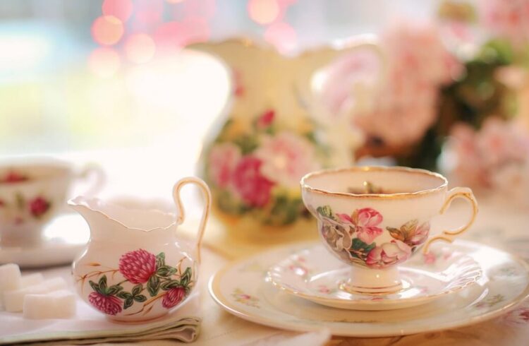 A floral tea cup on a saucer, with milk jug to the left