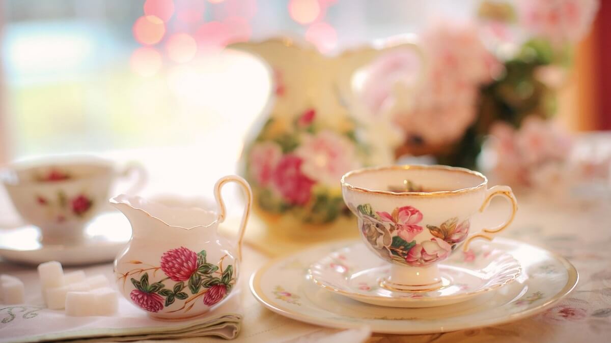 A floral tea cup on a saucer, with milk jug to the left